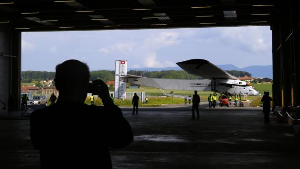 Das Solarflugzeug „Solar Impulse“ wird in einem Hangar von mehreren Personen vorbereitet.
