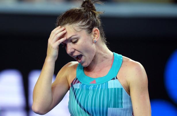 Eine Tennisspielerin mit schmerzverzerrtem Gesicht hält sich die Hand an die Stirn.