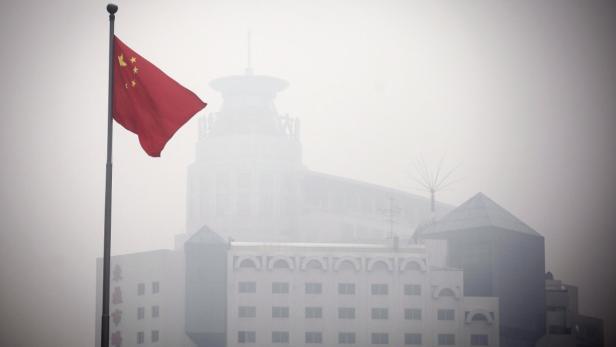Die chinesische Flagge weht vor einem Gebäude im Nebel.