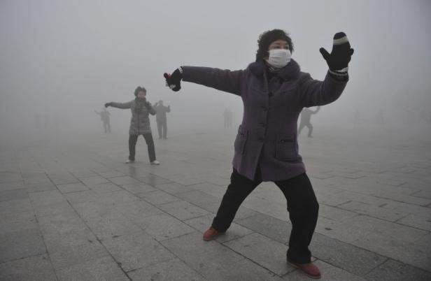 Eine Frau mit Gesichtsmaske praktiziert Tai-Chi im Nebel.