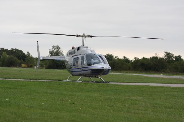 Ein silberner Hubschrauber steht auf einer Landebahn.