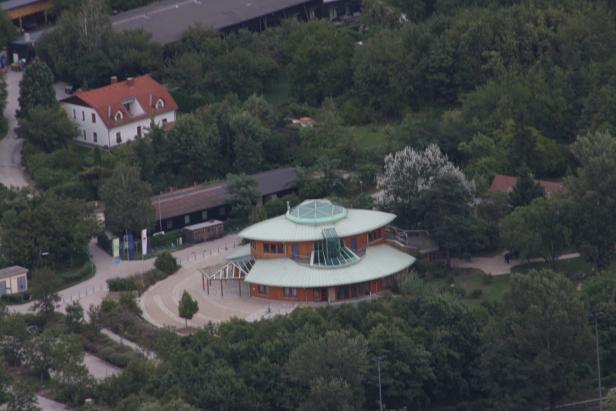 Ein ungewöhnliches, rundes Gebäude mit einem grünen Dach inmitten von Bäumen.