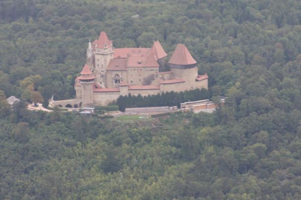 Burg Kreuzenstein thront auf einem bewaldeten Hügel.