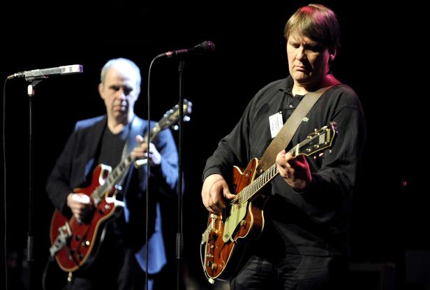 Zwei Männer spielen Gitarre auf einer Bühne.