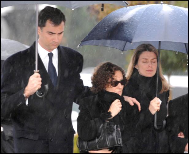 König Felipe VI. und Königin Letizia unter Regenschirmen bei einer Veranstaltung.