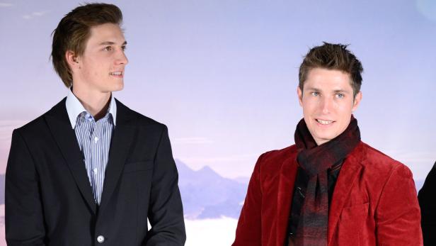 Zwei Männer posieren vor einem Hintergrund mit Bergmotiv.