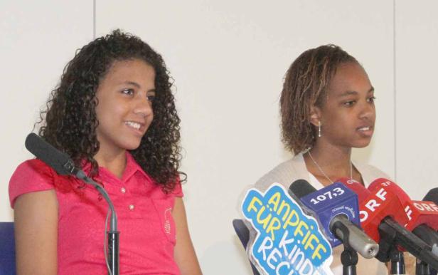 Zwei junge Frauen stehen vor Mikrofonen bei einer Pressekonferenz.