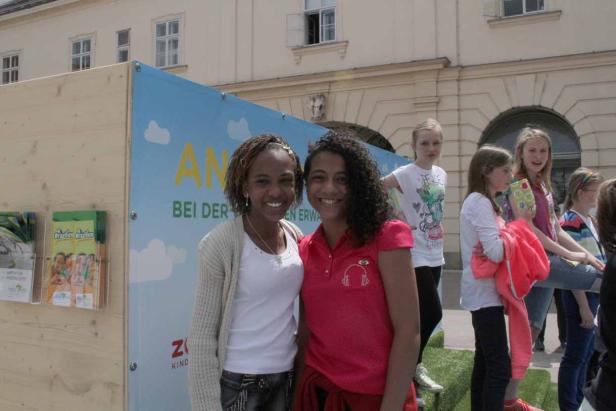 Zwei junge Frauen posieren lächelnd vor einem Stand mit der Aufschrift „An bei der Z Kind“.