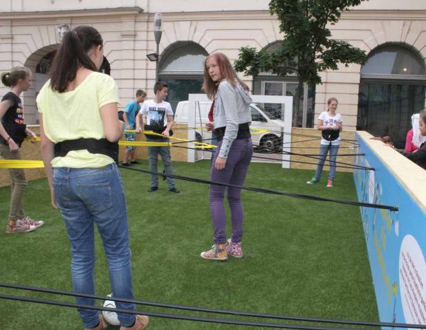 Eine Gruppe Jugendlicher spielt ein Spiel mit Hindernissen auf einer Rasenfläche.