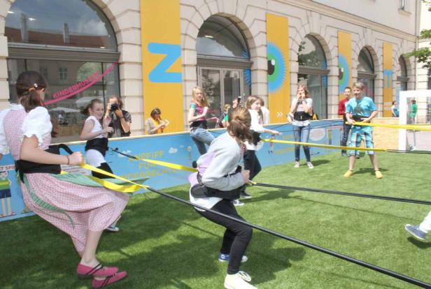 Kinder spielen ein Spiel mit Gummibändern vor dem Kindermuseum in Wien.