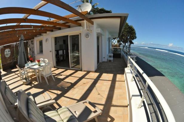 Eine Terrasse mit Meerblick, ausgestattet mit Tisch, Stühlen und Liegen.