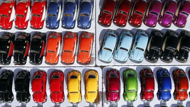 Viele bunte VW Käfer Modellautos in einer Vitrine.