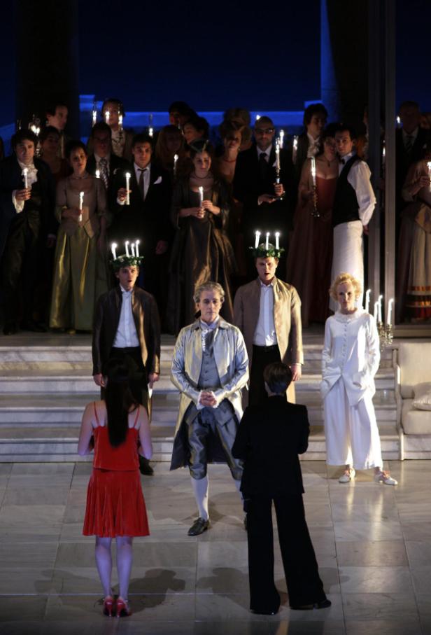 Eine Opernszene mit Darstellern in historischen Kostümen und Kerzen in der Hand.