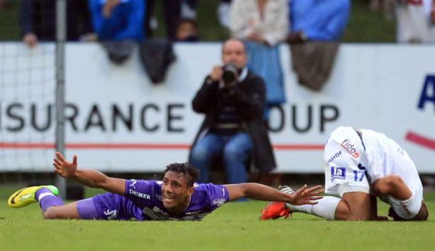 Ein Fußballspieler rutscht jubelnd auf dem Rasen, ein anderer kniet daneben.