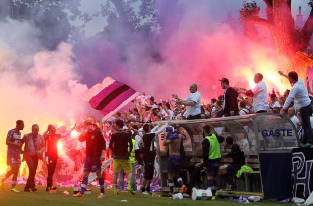 Fußballfans zünden Rauchbomben und Bengalos im Stadion.