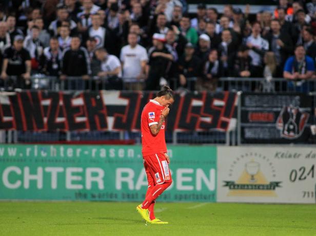 Ein Fußballspieler in roter Spielkleidung steht enttäuscht auf dem Spielfeld.