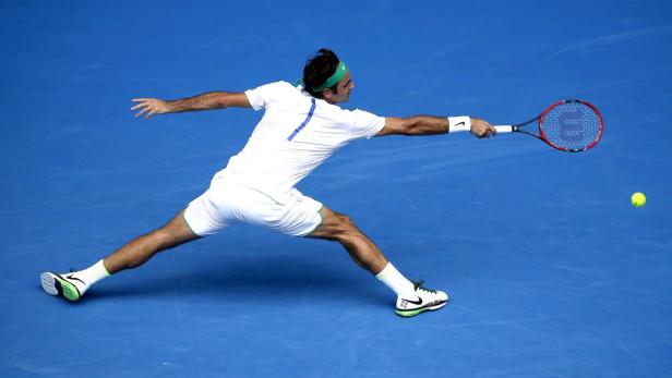 Roger Federer schlägt einen Tennisball auf einem blauen Platz.