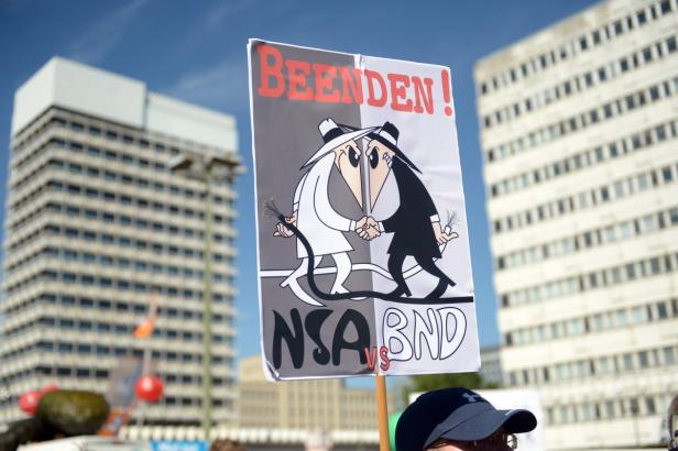 Ein Protestschild fordert das Ende von NSA und BND mit einer Karikatur von Spy vs. Spy.