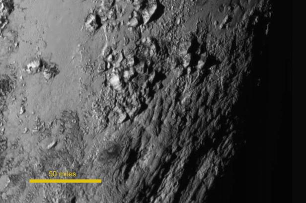 Eine Nahaufnahme der zerklüfteten Oberfläche des Pluto mit einer Entfernungsmarkierung von 50 Meilen.