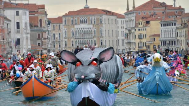 Geschmückte Boote, darunter eine riesige Ratte und ein Adler, fahren während des Karnevals durch Venedig.