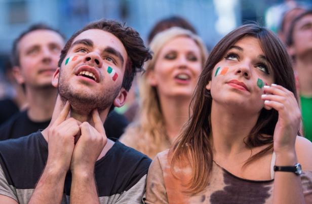 Zwei junge Fans mit italienischen Flaggen auf den Wangen schauen aufmerksam nach oben.