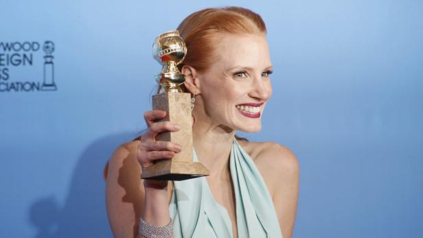 Jessica Chastain hält eine Golden Globe Trophäe in der Hand und lächelt.