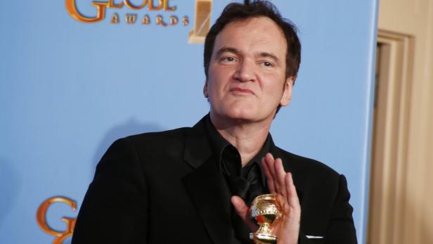 Quentin Tarantino hält eine goldene Trophäe in der Hand.