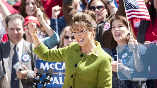 Sarah Palin spricht vor einer jubelnden Menge mit amerikanischer Flagge.