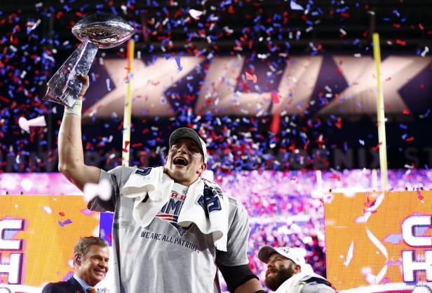 Ein Footballspieler der New England Patriots feiert mit der Vince Lombardi Trophy im Konfettiregen.