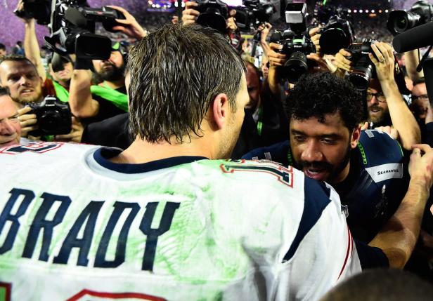 Tom Brady und Russell Wilson umringt von Fotografen.