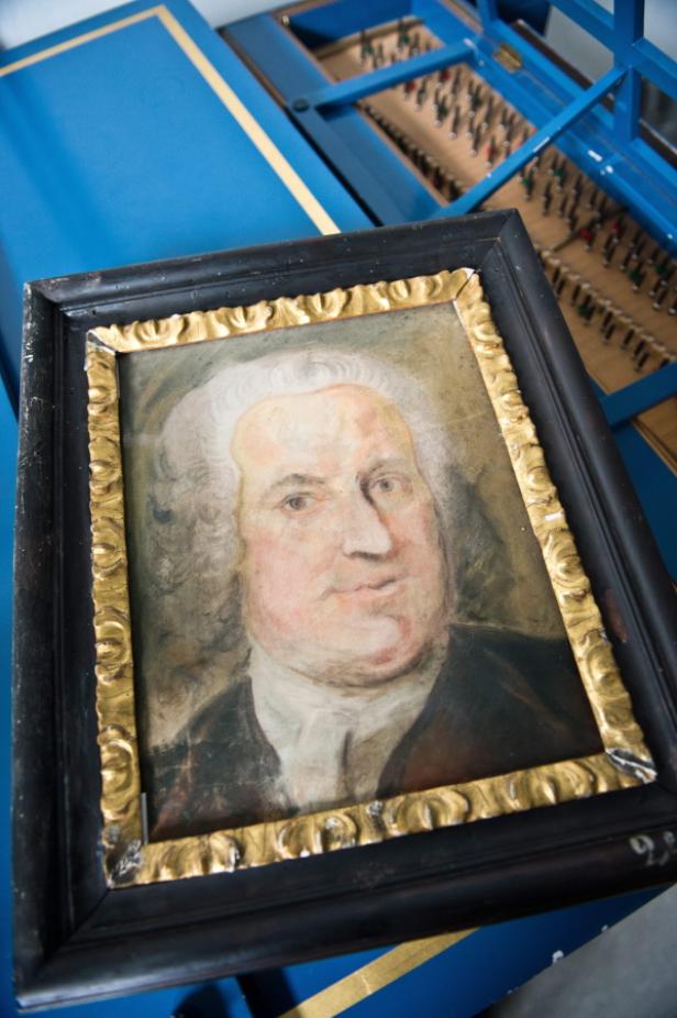 Ein gerahmtes Porträt eines Mannes mit weißer Perücke.