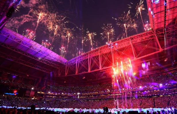Feuerwerk über einem vollbesetzten Stadion bei Nacht.