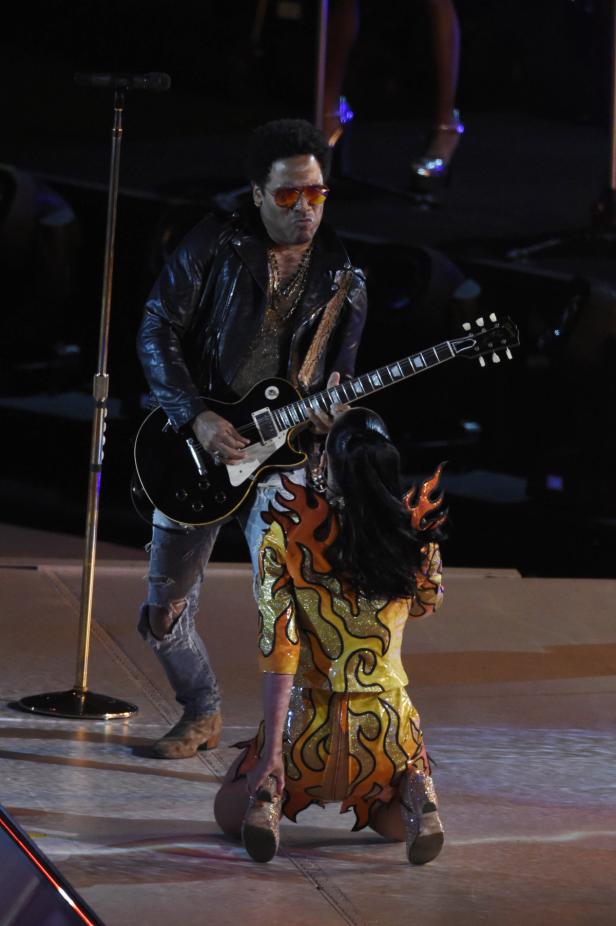 Lenny Kravitz spielt Gitarre, während Katy Perry auf der Bühne kniet.