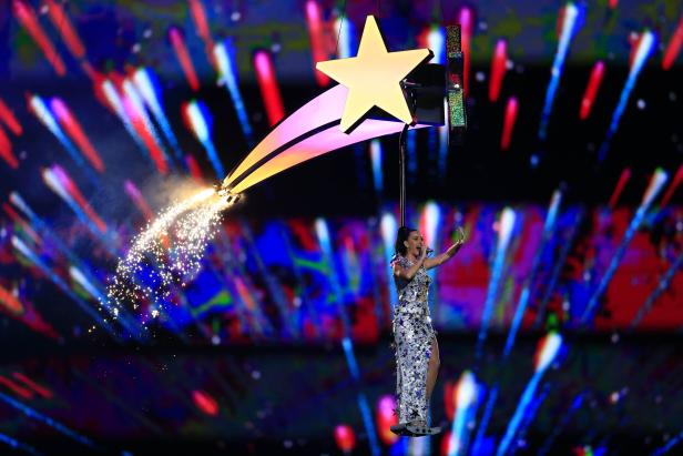 Katy Perry schwebt an einem Stern hängend über der Bühne, während Funken sprühen.