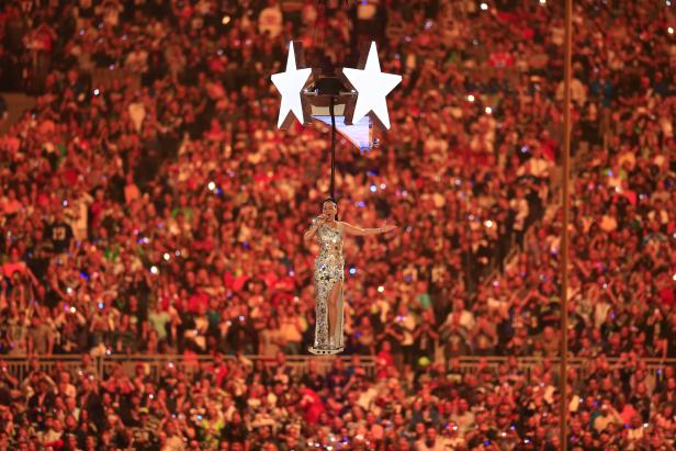 Katy Perry schwebt während eines Konzerts an zwei großen Sternen über die Menge.
