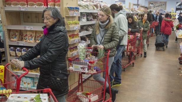 Eine Schlange von Kunden mit Einkaufswagen in einem Supermarkt.