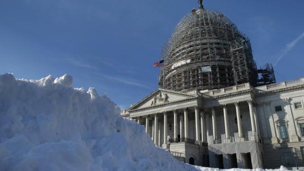 Das U.S. Capitol Building mit einer Schneewehe im Vordergrund und Baugerüsten an der Kuppel.