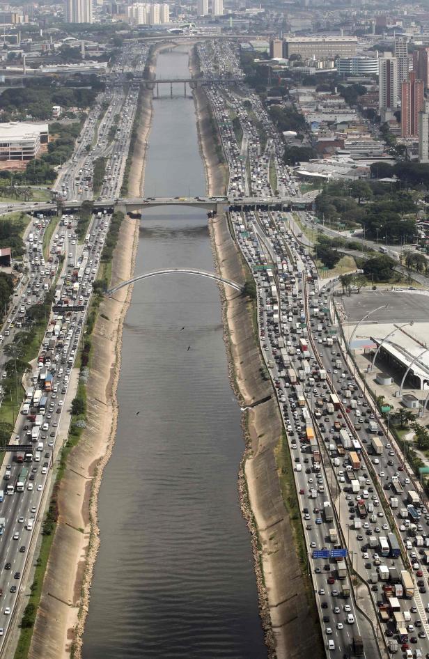 Luftaufnahme einer stark befahrenen Autobahn neben einem Fluss in einer Stadt.