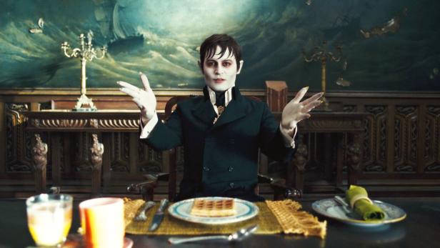 Barnabas Collins (Johnny Depp) sitzt an einem Tisch mit einer Waffel vor sich.