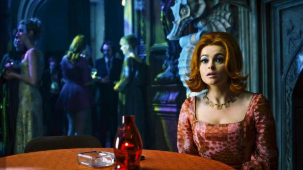 Helena Bonham Carter in einem gemusterten Kleid an einem Tisch auf einer Party.