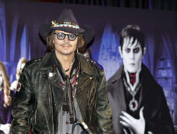 Johnny Depp posiert vor einem Poster des Films „Dark Shadows“.