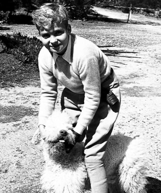 Ein junger Mann umarmt einen großen, zotteligen Hund im Freien.