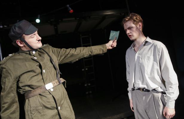 Ein Soldat in Uniform zeigt einem jungen Mann einen Ausweis.