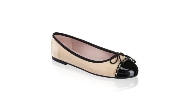 Ein beiger Ballerina-Schuh mit schwarzer Spitze und Schleife.