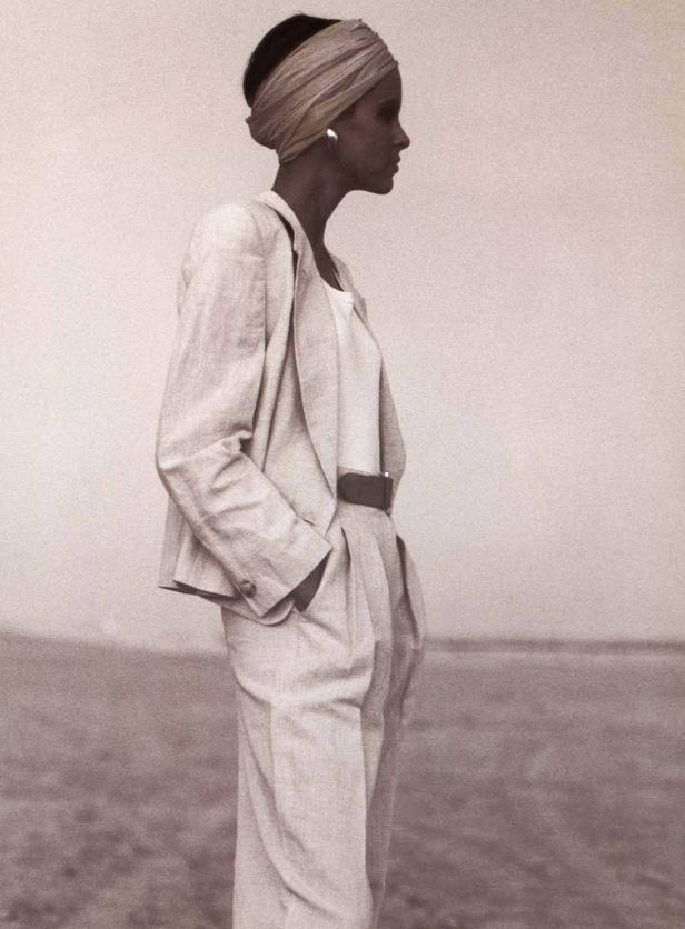 Eine Frau mit Turban und hellem Anzug steht auf einer Ebene.