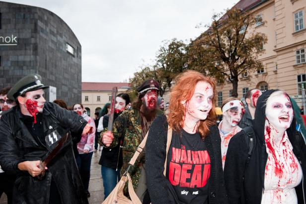 Eine Gruppe als Zombies verkleideter Menschen nimmt an einer Parade teil.