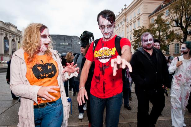 Eine Gruppe als Zombies verkleideter Menschen nimmt an einer Parade teil.