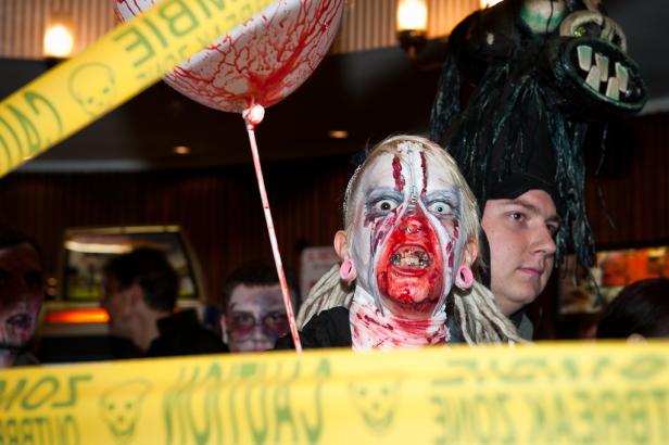 Eine Person mit Zombie-Make-up und ein Ballon mit Blutflecken auf einer Halloween-Party.