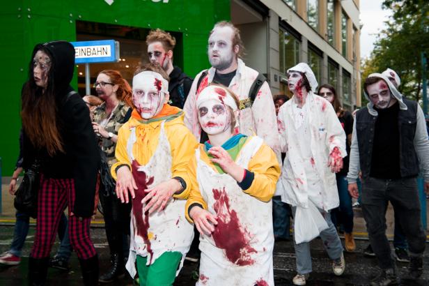 Eine Gruppe als Zombies verkleideter Menschen nimmt an einer Parade teil.