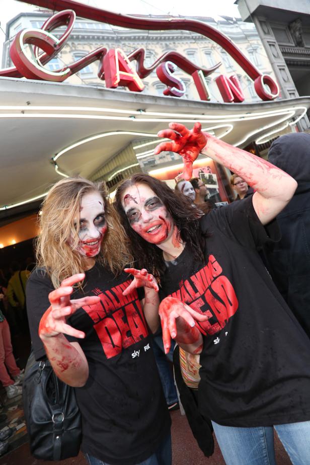 Zwei Frauen in „The Walking Dead“-T-Shirts und Zombie-Make-up posieren vor einem Casino.